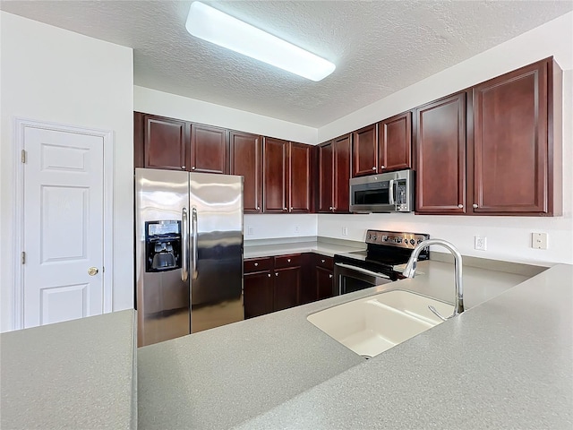 kitchen with appliances with stainless steel finishes, sink, and a textured ceiling