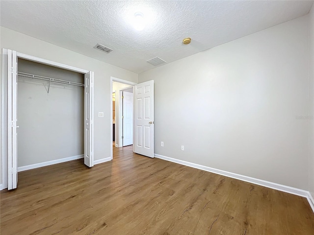 unfurnished bedroom with hardwood / wood-style flooring, a textured ceiling, and a closet