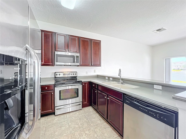 kitchen with sink, light tile patterned flooring, a textured ceiling, and appliances with stainless steel finishes