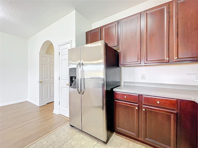 kitchen with stainless steel fridge, a textured ceiling, and light tile patterned flooring