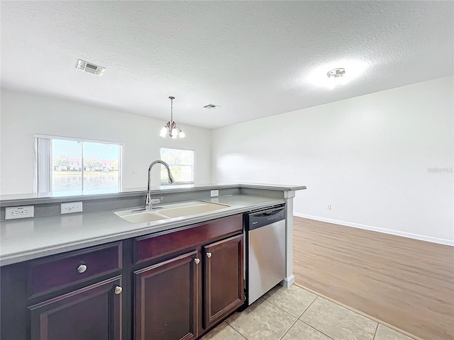 kitchen featuring sink, light tile patterned floors, a textured ceiling, decorative light fixtures, and stainless steel dishwasher