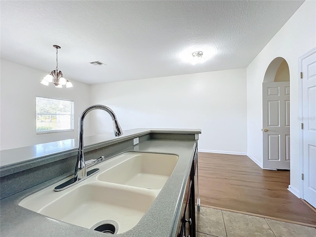 kitchen with sink, hanging light fixtures, a notable chandelier, tile patterned floors, and a textured ceiling