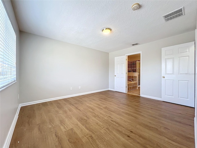 unfurnished bedroom with hardwood / wood-style flooring and a textured ceiling