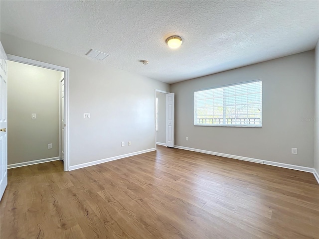 spare room featuring light hardwood / wood-style flooring and a textured ceiling