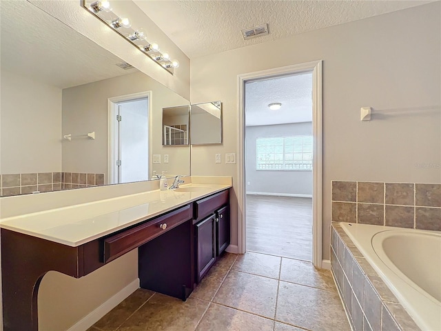 bathroom with vanity, tiled bath, tile patterned flooring, and a textured ceiling