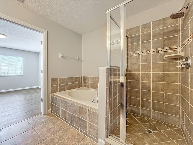 bathroom with tile patterned floors, shower with separate bathtub, and a textured ceiling