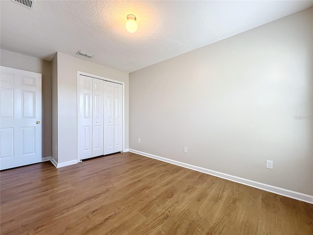 unfurnished bedroom featuring wood-type flooring, a textured ceiling, and a closet