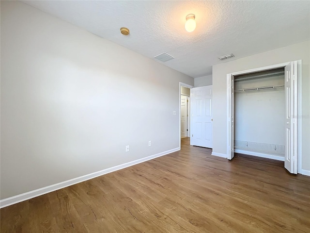 unfurnished bedroom with hardwood / wood-style flooring, a closet, and a textured ceiling