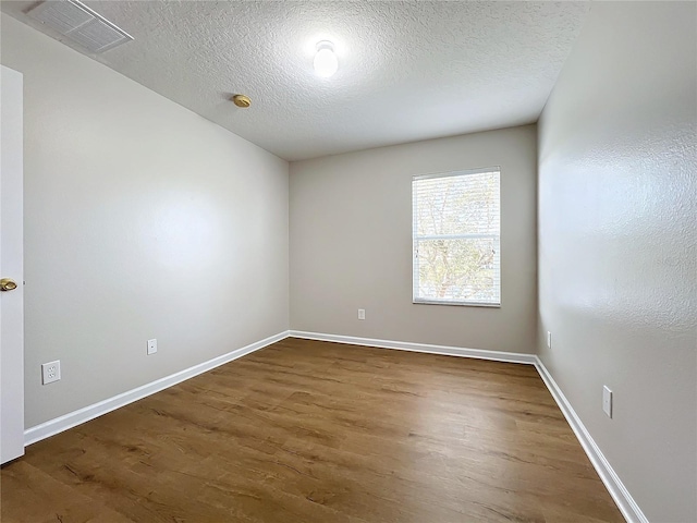 spare room featuring dark hardwood / wood-style floors and a textured ceiling