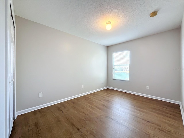 spare room featuring dark hardwood / wood-style floors and a textured ceiling