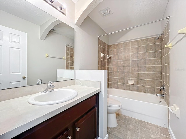 full bathroom with tiled shower / bath, vanity, toilet, tile patterned floors, and a textured ceiling