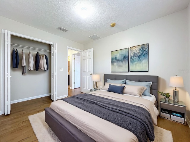 bedroom featuring hardwood / wood-style flooring, a textured ceiling, and a closet