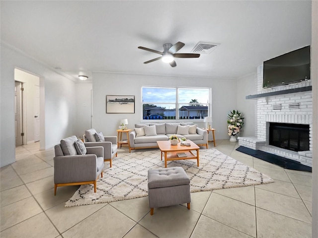 living room with a fireplace, ornamental molding, ceiling fan, and light tile patterned flooring