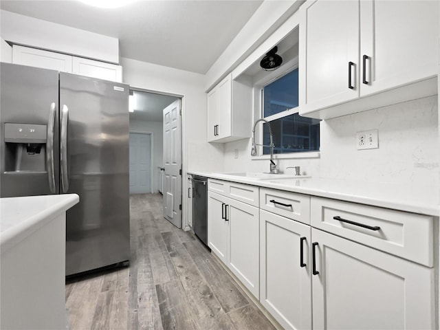 kitchen with sink, white cabinets, light hardwood / wood-style floors, and appliances with stainless steel finishes