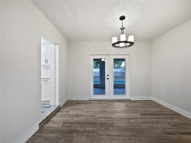 interior space featuring french doors, dark wood-type flooring, a textured ceiling, and a notable chandelier