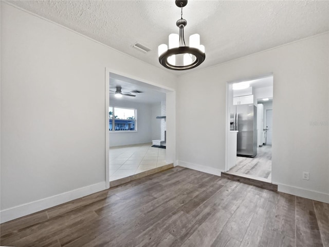 unfurnished dining area featuring a textured ceiling, a notable chandelier, and light wood-type flooring