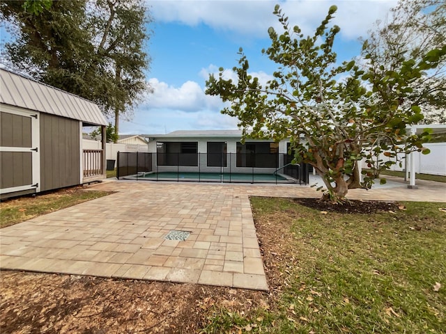 back of property with a shed, a fenced in pool, and a patio