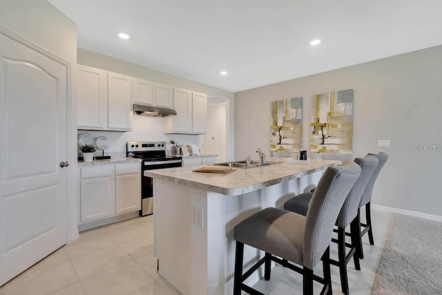 kitchen featuring stainless steel electric stove, white cabinetry, sink, a kitchen island with sink, and a breakfast bar area