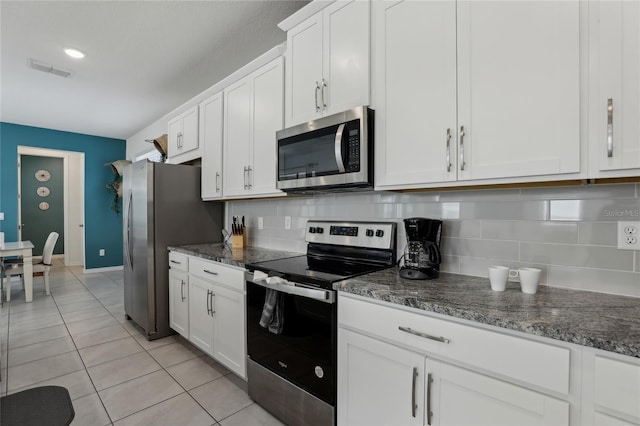 kitchen featuring white cabinets, backsplash, appliances with stainless steel finishes, and dark stone counters