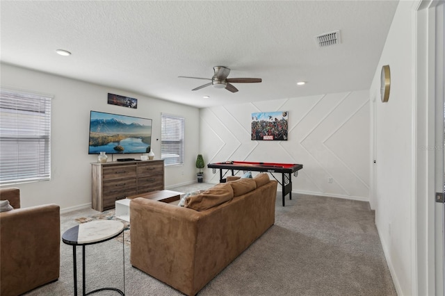 carpeted living room featuring ceiling fan and a textured ceiling