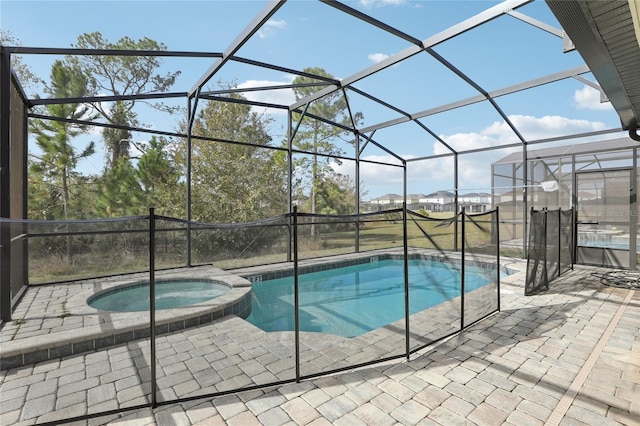 view of pool featuring glass enclosure, an in ground hot tub, and a patio area