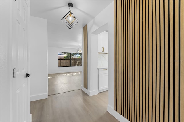 hallway featuring an inviting chandelier and light hardwood / wood-style floors