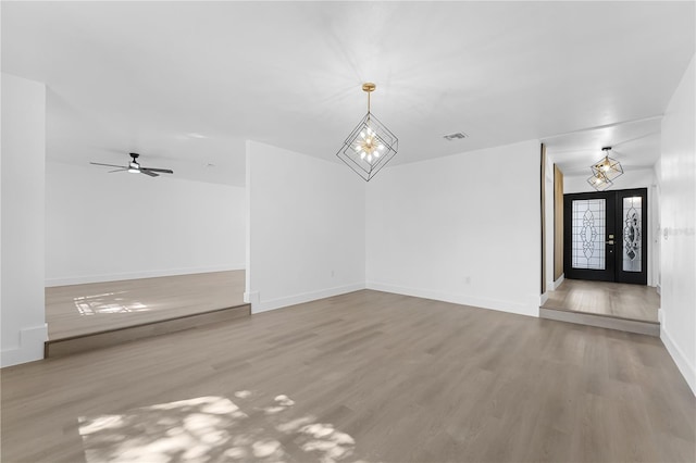 unfurnished living room with hardwood / wood-style flooring, an inviting chandelier, and french doors