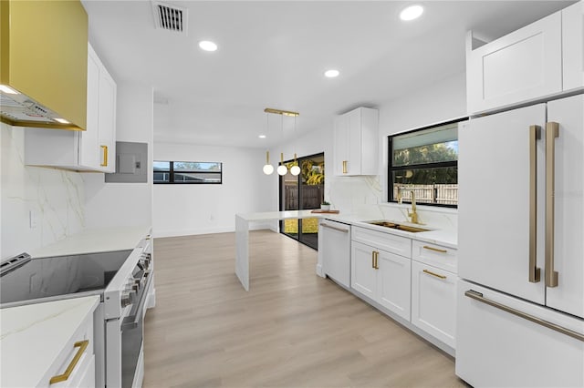 kitchen with sink, white appliances, white cabinetry, hanging light fixtures, and light stone counters