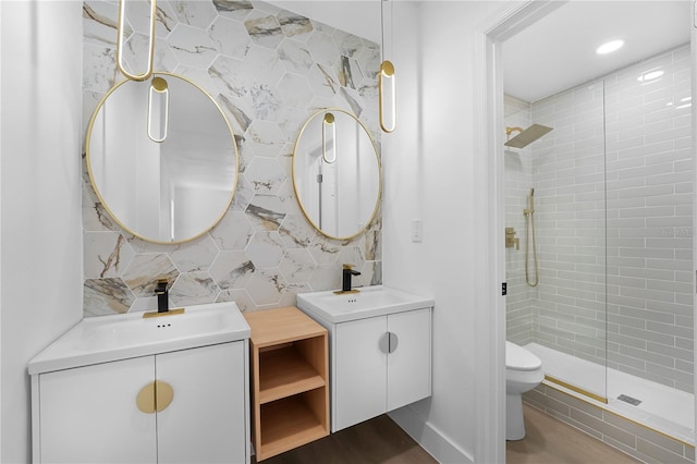 bathroom with toilet, tile walls, a tile shower, vanity, and backsplash