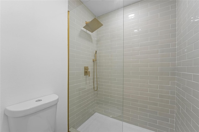 bathroom featuring a tile shower and toilet