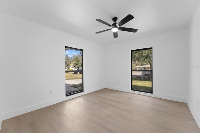 spare room featuring ceiling fan, a wealth of natural light, and light wood-type flooring