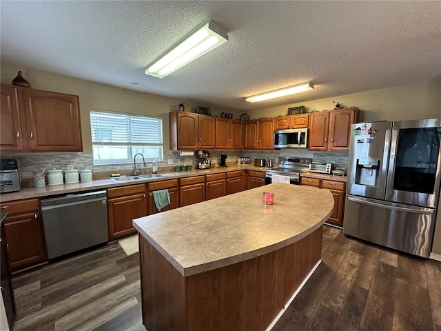 kitchen with a textured ceiling, a kitchen island, dark wood-type flooring, stainless steel appliances, and sink