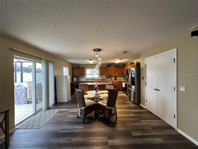 dining area with sink, a textured ceiling, and dark hardwood / wood-style flooring