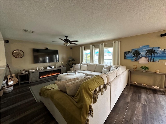 living room with ceiling fan, dark hardwood / wood-style floors, and a textured ceiling