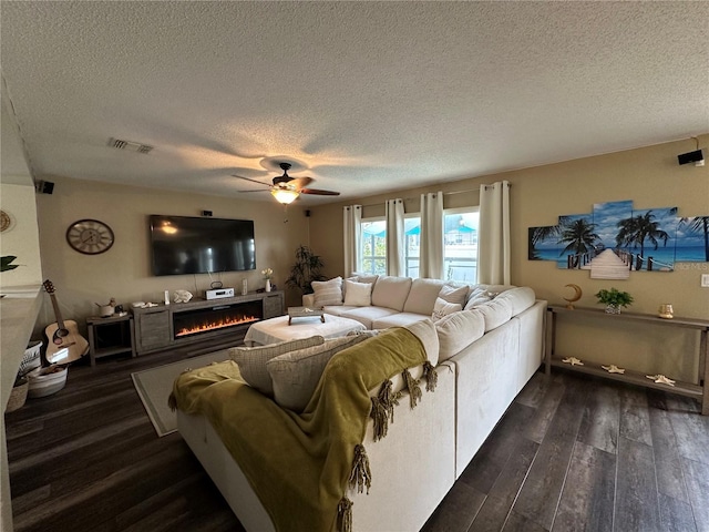 living room with ceiling fan, a textured ceiling, and dark hardwood / wood-style flooring