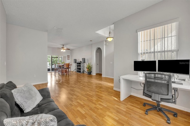 office area with ceiling fan, light wood-type flooring, and a textured ceiling