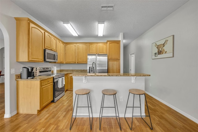 kitchen with light stone countertops, stainless steel appliances, a breakfast bar, and a kitchen island