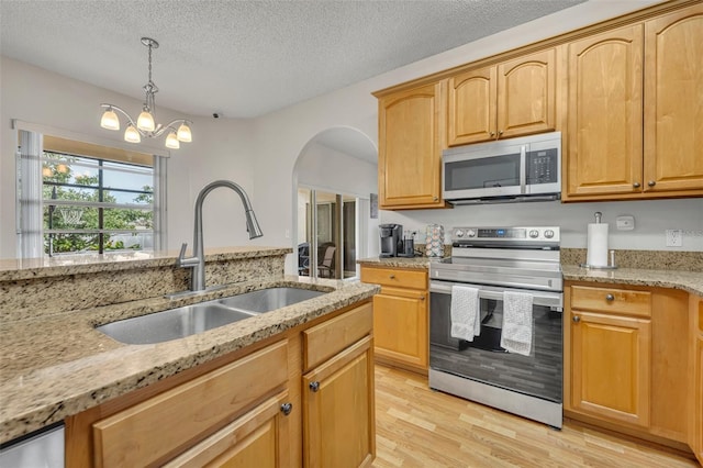 kitchen with light hardwood / wood-style floors, sink, light stone countertops, stainless steel appliances, and a textured ceiling