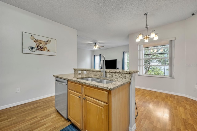 kitchen with stainless steel dishwasher, an island with sink, sink, and a textured ceiling