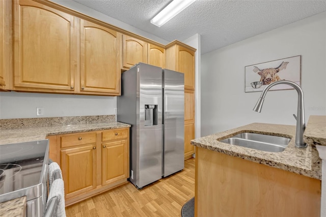 kitchen featuring stainless steel appliances, light stone counters, and sink