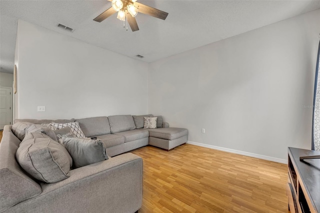 living room featuring ceiling fan, a textured ceiling, and hardwood / wood-style flooring