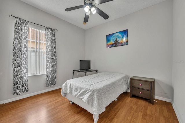 bedroom with ceiling fan, hardwood / wood-style floors, and a textured ceiling