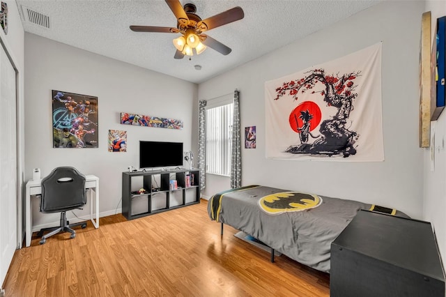 bedroom with a textured ceiling, ceiling fan, and hardwood / wood-style flooring