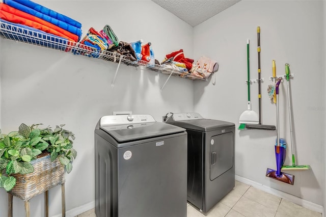 washroom with a textured ceiling, separate washer and dryer, and light tile patterned flooring