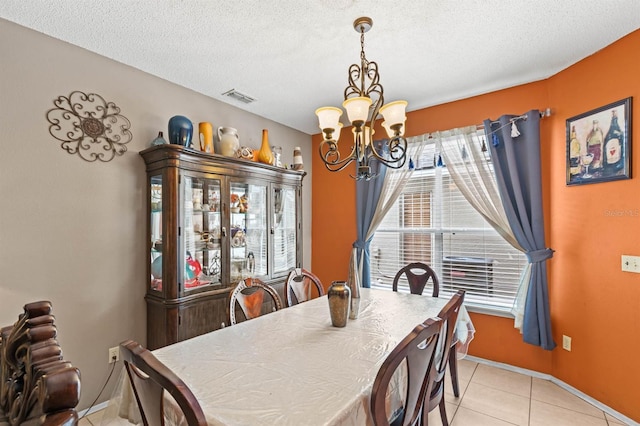 dining room featuring light tile patterned flooring, a textured ceiling, and an inviting chandelier