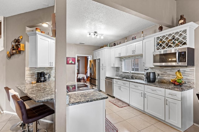 kitchen featuring tasteful backsplash, white cabinetry, appliances with stainless steel finishes, and sink