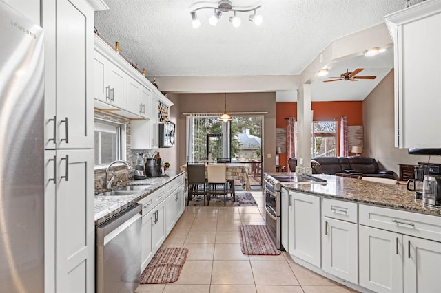 kitchen featuring appliances with stainless steel finishes, sink, light tile patterned floors, and white cabinets