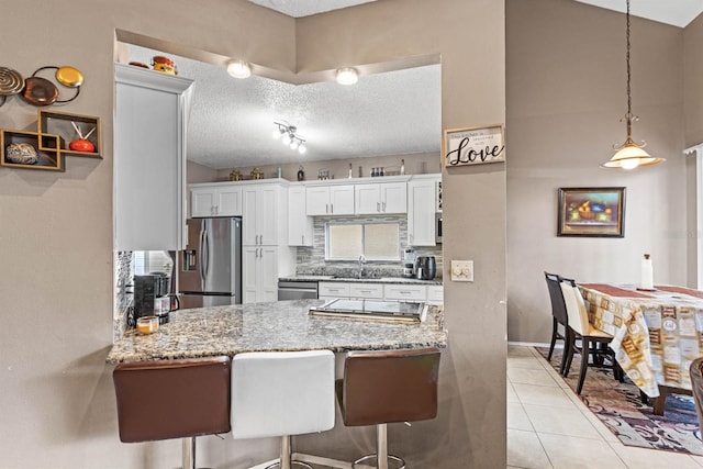 kitchen with sink, a breakfast bar, white cabinets, and appliances with stainless steel finishes