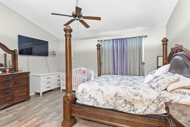 bedroom featuring lofted ceiling, a textured ceiling, light hardwood / wood-style floors, and ceiling fan