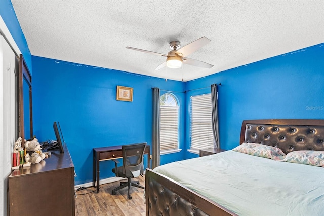 bedroom with wood-type flooring, a textured ceiling, ceiling fan, and a closet